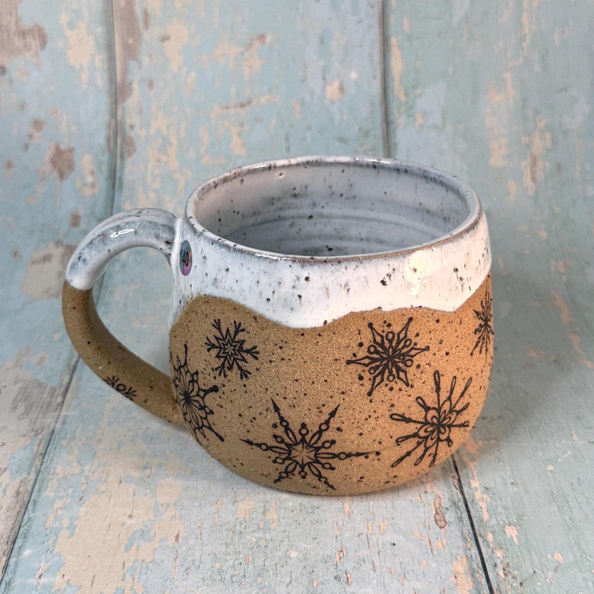 Stoneware holiday mug decorated with snowflakes and white glaze
